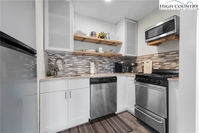 a kitchen with stainless steel appliances granite countertop a stove a sink and a refrigerator