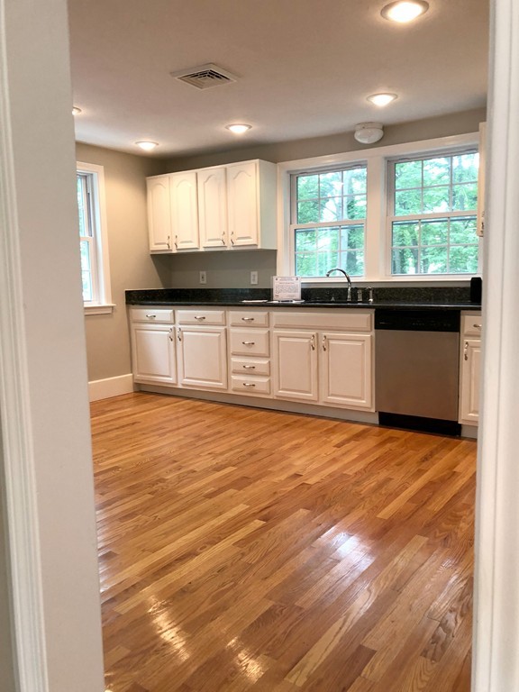 9 Colonial Road Milford, MA 01757 - Photo 7 of 16 a kitchen with stainless steel appliances granite countertop a stove a sink and white cabinets with wooden floor