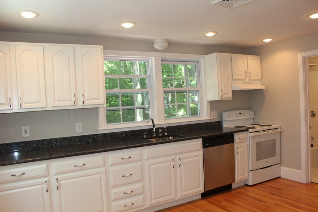 9 Colonial Road Milford, MA 01757 - Photo 8 of 16 a kitchen with granite countertop white cabinets white appliances a sink and a window