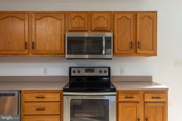 a kitchen with granite countertop wood cabinets stainless steel appliances and a sink