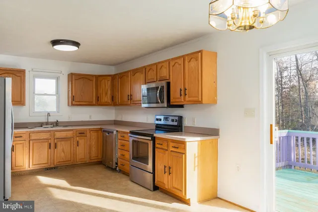 a kitchen with stainless steel appliances granite countertop a refrigerator a sink dishwasher a stove and a dining table with wooden floor