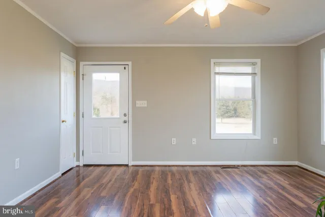 an empty room with wooden floor and windows