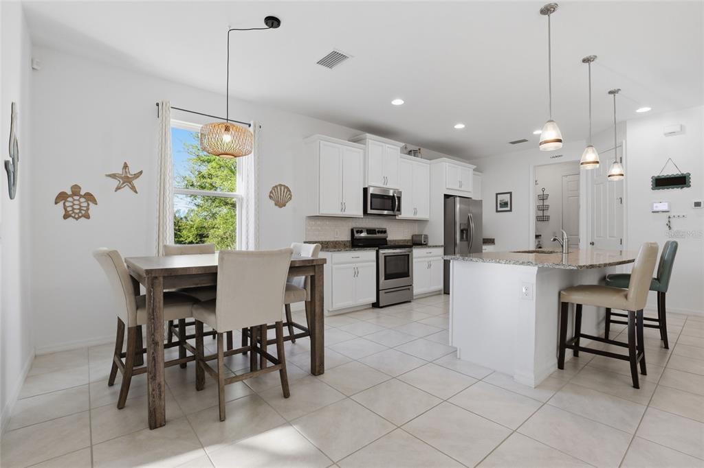 14879 Wichita Road Port Charlotte, FL 33981 - Photo 16 of 45 a kitchen with kitchen island a dining table chairs and white cabinets