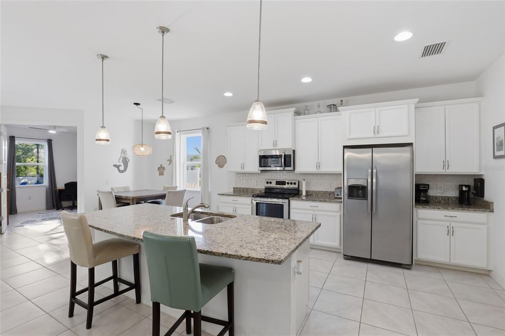 14879 Wichita Road Port Charlotte, FL 33981 - Photo 10 of 45 a kitchen with granite countertop a refrigerator a sink a stove a dining table and chairs