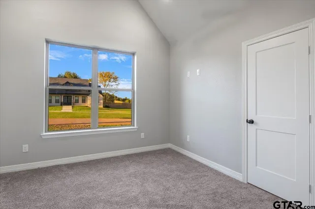an empty room with wooden floor chandelier and windows