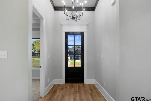 an empty room with wooden floor chandelier and entryway