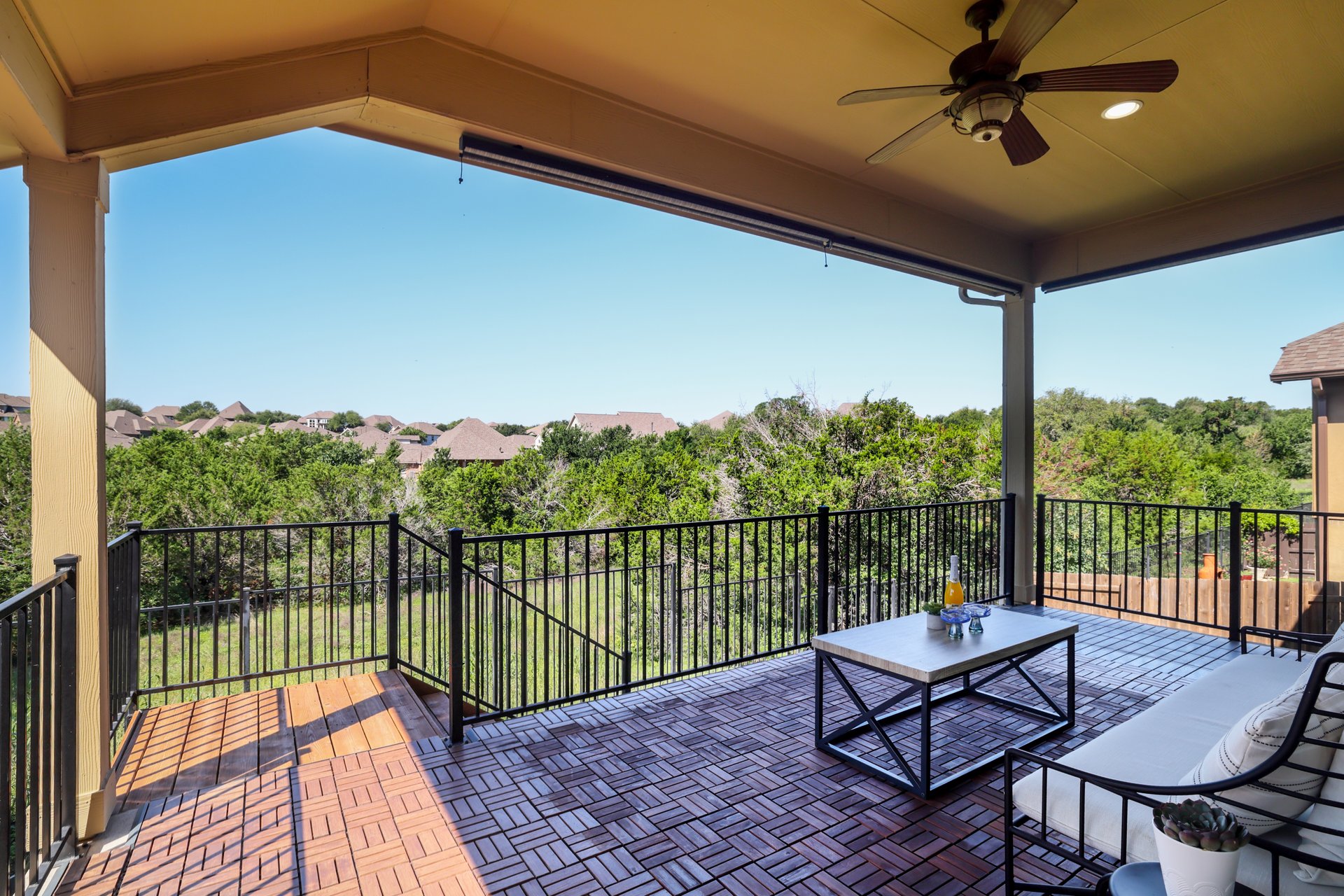 173 Santa Maria Street Georgetown, TX 78628 - Photo 33 of 39 Covered outdoor patio featuring a ceiling fan with integrated lighting, wood-finish flooring tiles, and dark metal railings
