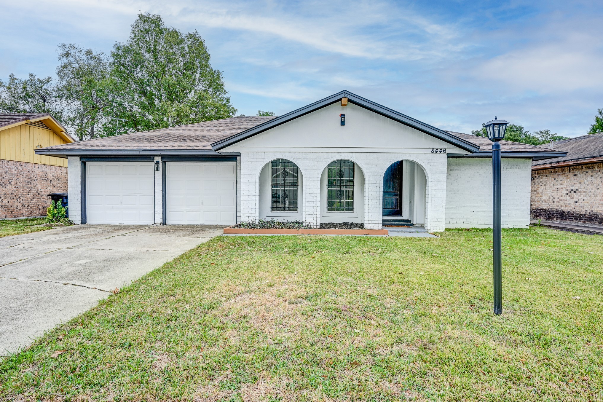 a view of a white house with a small yard and large tree