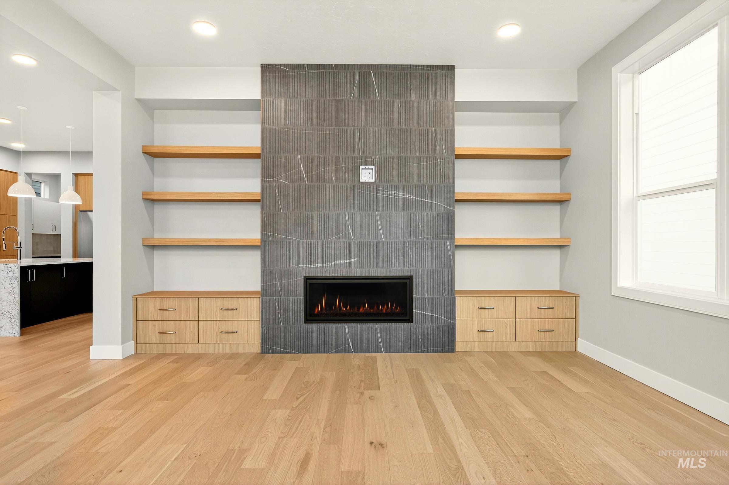 3374 West Neville Rnch Drive Boise, ID 83714 - Photo 6 of 37 Unfurnished living room featuring recessed lighting, light wood-style flooring, a tiled fireplace, and built in features