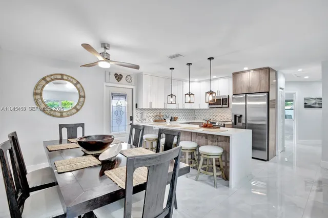 a kitchen with stainless steel appliances a dining table chairs and a refrigerator