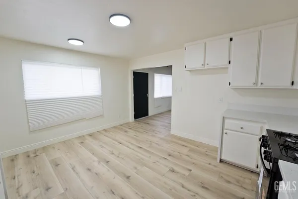 a view of an empty room with wooden floor and cabinet
