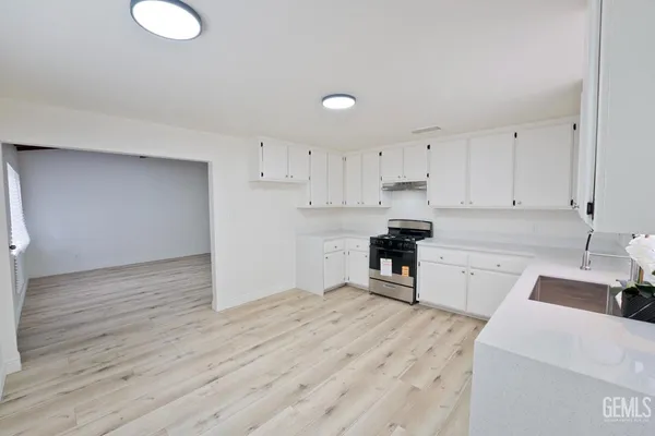 a kitchen with a refrigerator a stove top oven and white cabinets