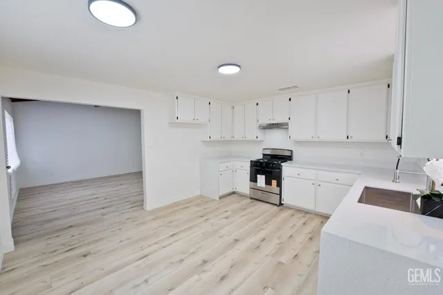 a kitchen with a refrigerator a stove top oven and white cabinets