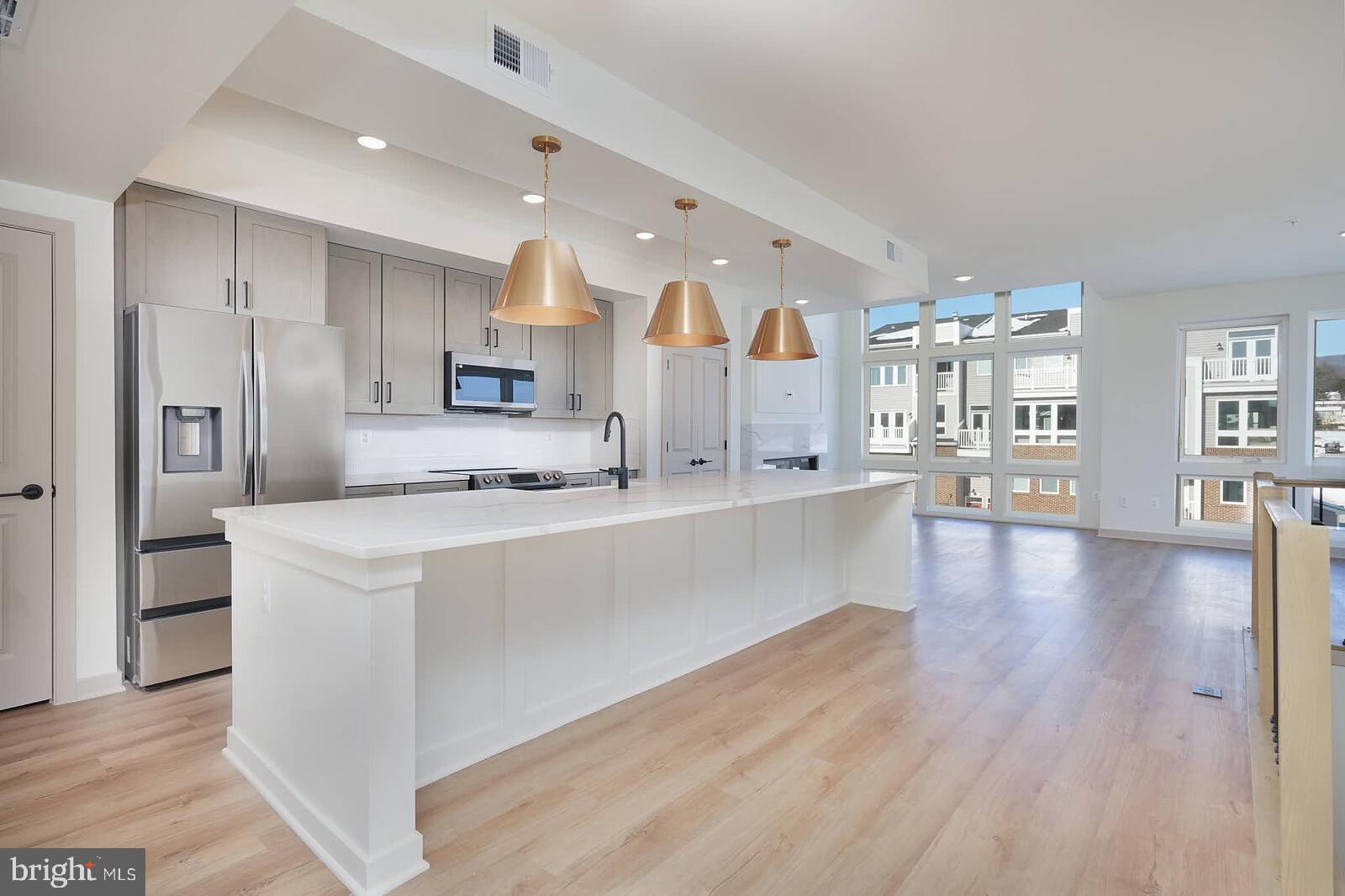 a large kitchen with stainless steel appliances a large counter top and a wooden floors