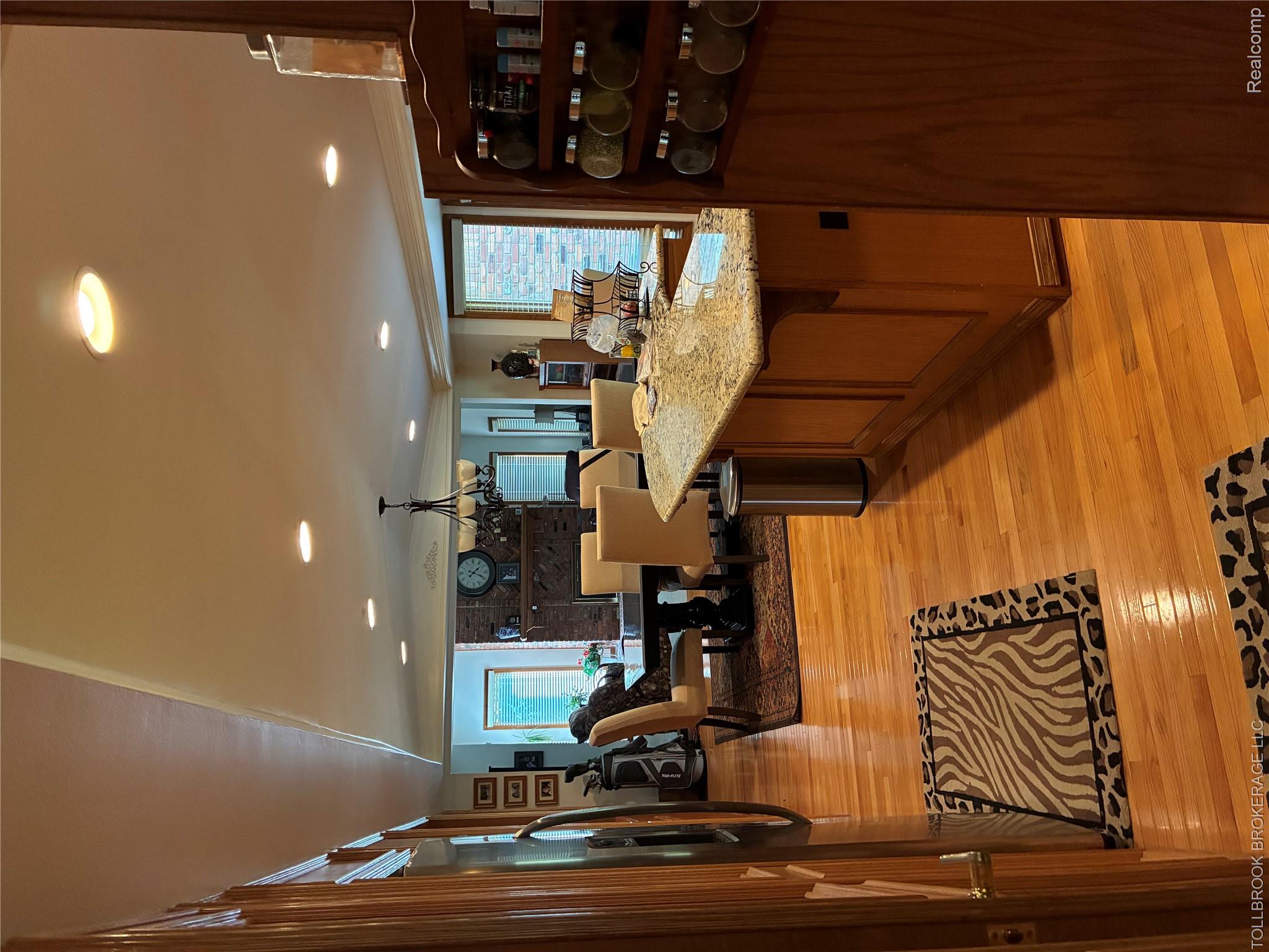 6187 Country Ridge Drive Troy, MI 48098 - Photo 8 of 23 Spacious kitchen featuring warm wood cabinetry, granite-topped island with seating, recessed and pendant lighting, and hardwood flooring
