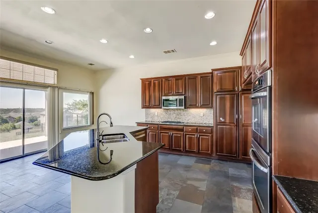 a kitchen with stainless steel appliances granite countertop a refrigerator a stove and a sink