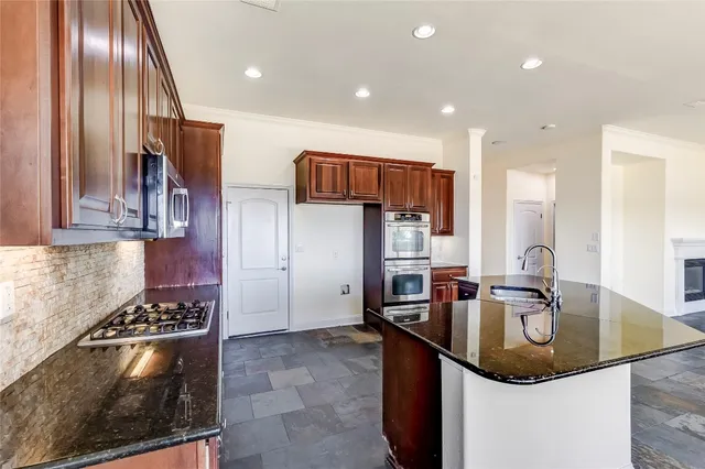 a kitchen with stainless steel appliances granite countertop a sink a stove and a refrigerator