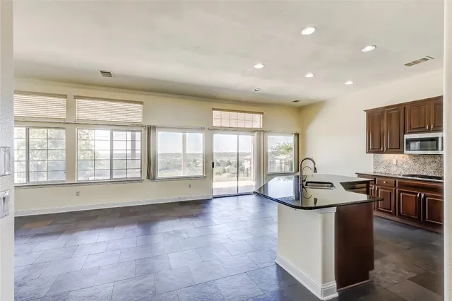 a large kitchen with kitchen island granite countertop a sink and a stove top oven with wooden floor