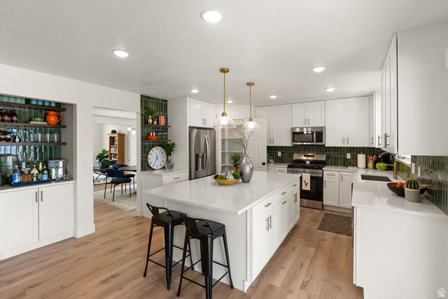 368 Spring Creek Road Providence, UT 84332 - Photo 3 of 45 Kitchen with white cabinetry, stainless steel appliances, a center island, light stone counters, and hanging light fixtures