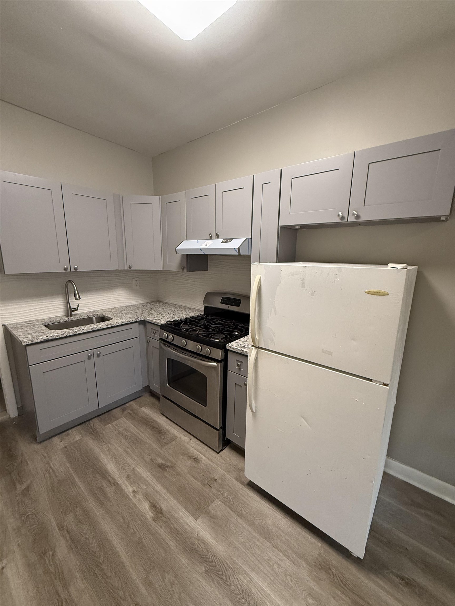 303 Broadway, Unit 1A Bayonne, NJ 07002 - Photo 2 of 6 a kitchen with a white cabinets and white appliances