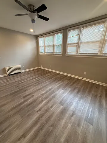 an empty room with wooden floor fan and windows
