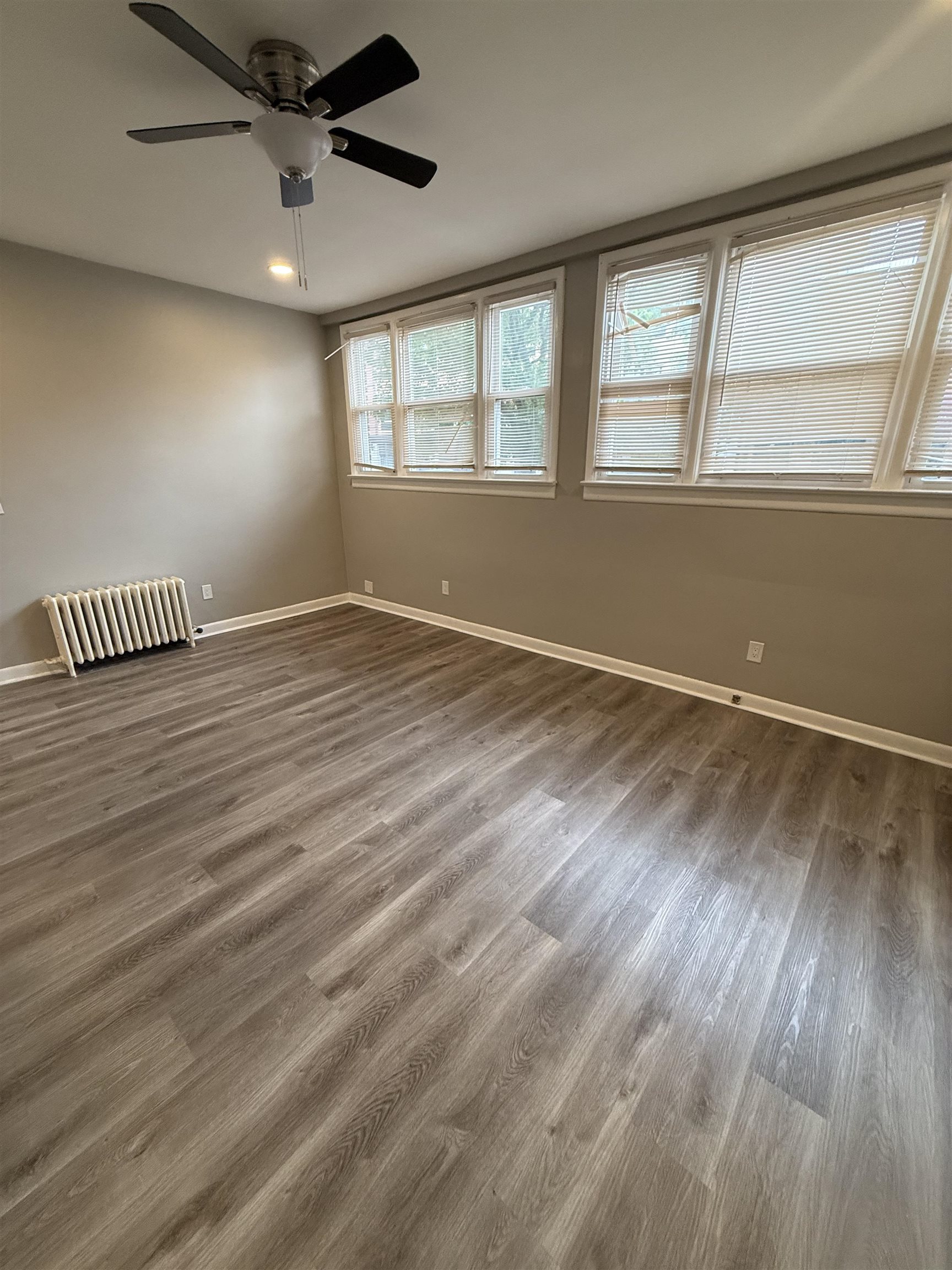 303 Broadway, Unit 1A Bayonne, NJ 07002 - Photo 4 of 6 an empty room with wooden floor fan and windows