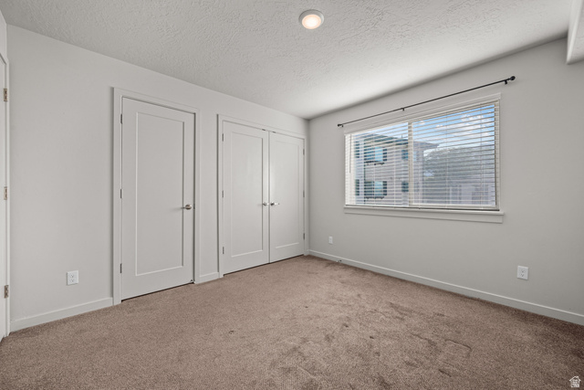 1700 South Sandhill Road West, Unit E 301 Orem, UT 84058 - Photo 11 of 20 Room featuring neutral-toned carpet flooring, a large window with horizontal blinds, and a surface-mounted ceiling light fixture