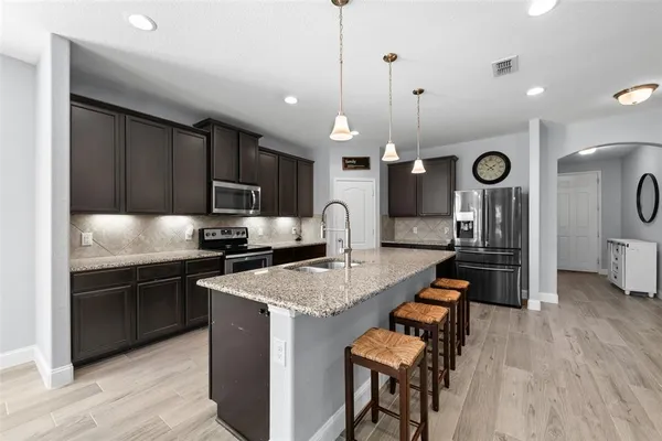 a kitchen with granite countertop a table chairs microwave and cabinets