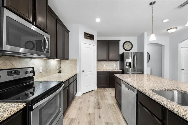 a kitchen with stainless steel appliances granite countertop a sink refrigerator and cabinets