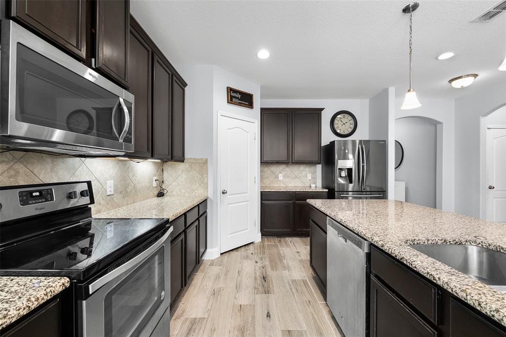 3709 Juniperio Street Denton, TX 76208 - Photo 11 of 31 a kitchen with stainless steel appliances granite countertop a sink a stove and a wooden floors