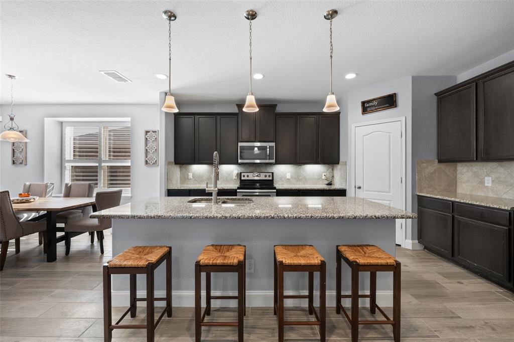 3709 Juniperio Street Denton, TX 76208 - Photo 9 of 31 a kitchen with granite countertop a table chairs microwave and cabinets