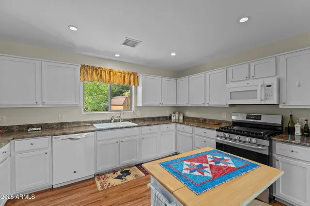 a kitchen with kitchen island granite countertop a sink cabinets and wooden floor