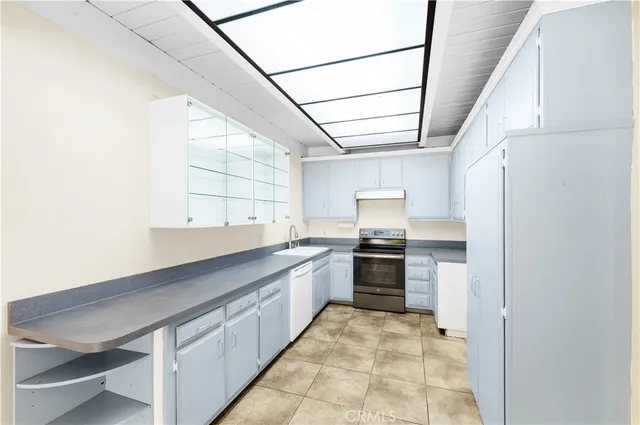 a large kitchen with a sink and dishwasher a stove top oven with wooden floor