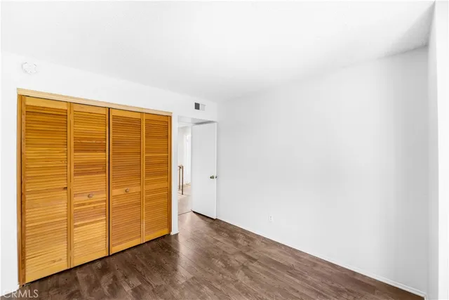 an empty room with wooden floor and cabinet