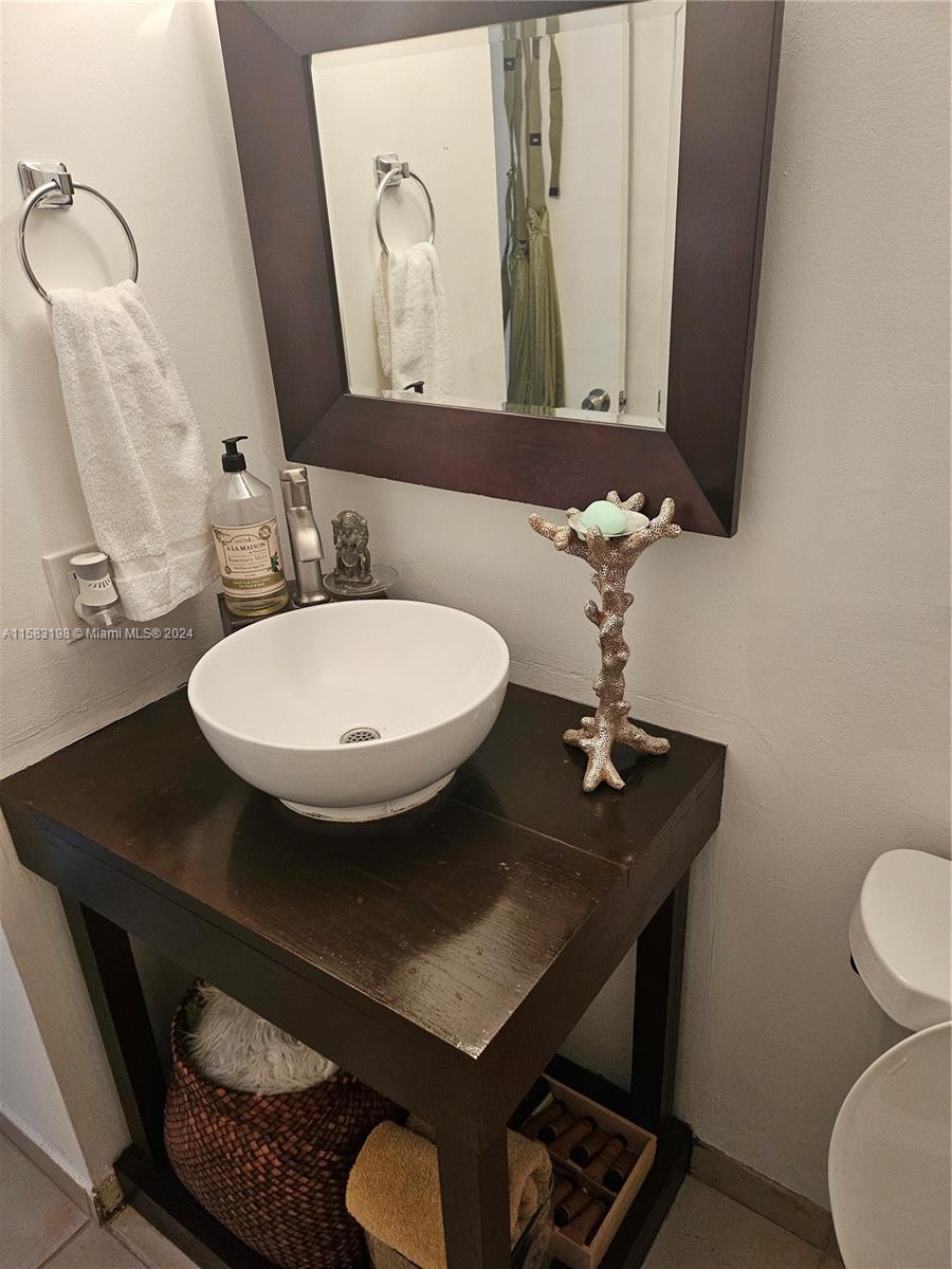 1605 Bay Road, Unit 406 Miami Beach, FL 33139 - Photo 11 of 31 a bathroom with a sink a mirror a toilet and a mirror