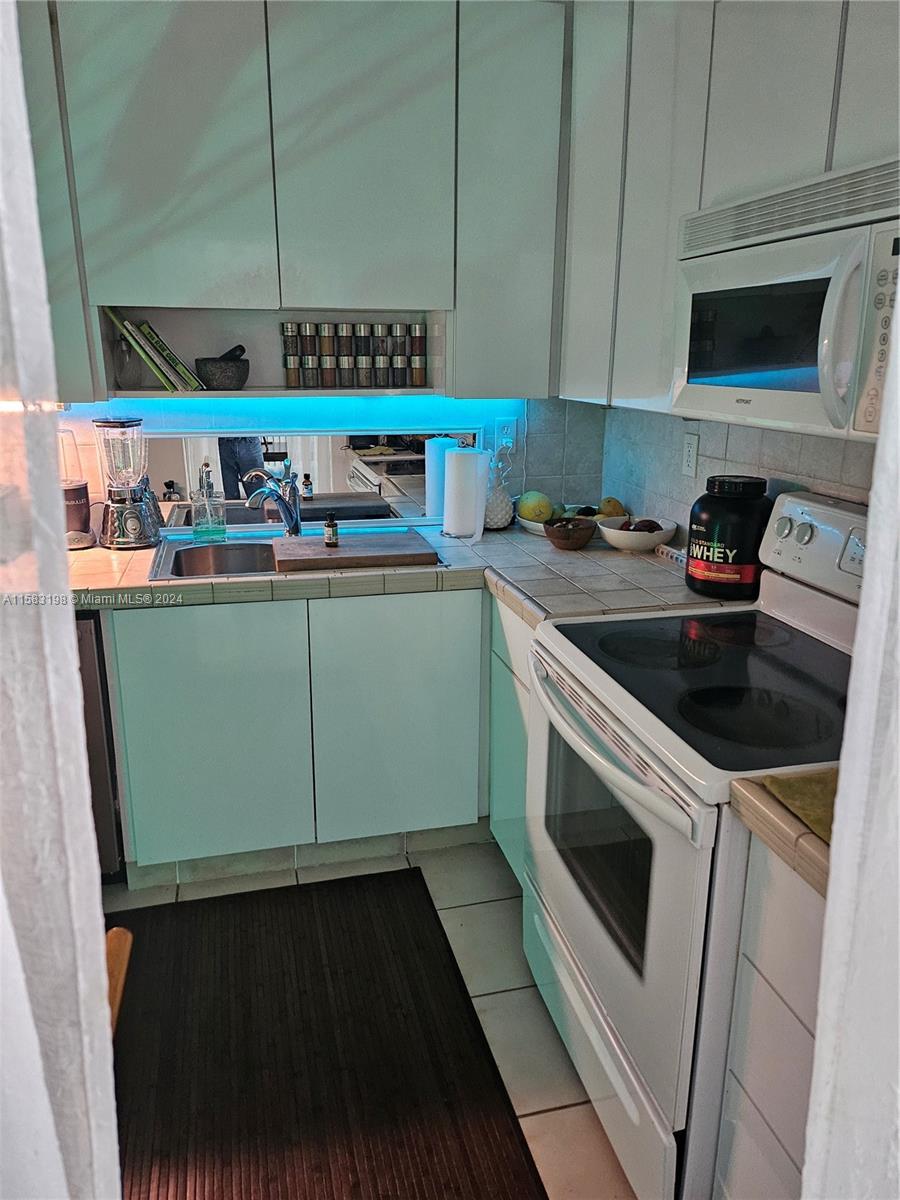 1605 Bay Road, Unit 406 Miami Beach, FL 33139 - Photo 25 of 31 a kitchen with stainless steel appliances granite countertop a stove a sink and a microwave