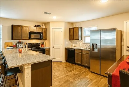 a kitchen with stainless steel appliances granite countertop a refrigerator a stove and a sink