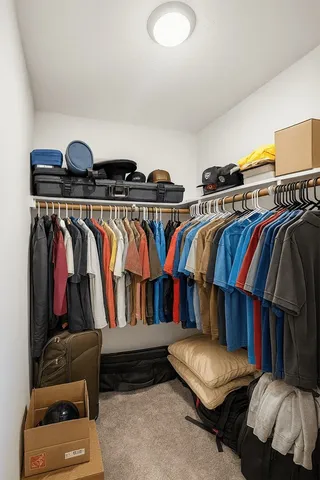 a view of walk in closet with clothes and shoes