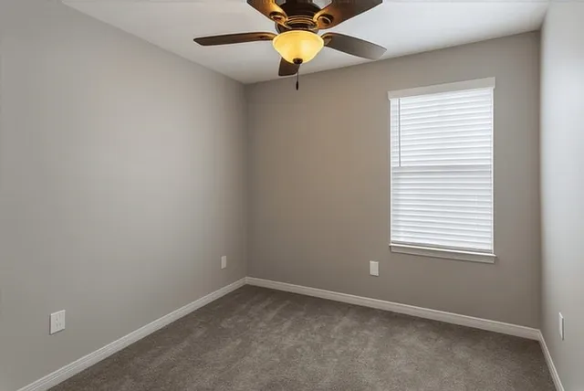 an empty room with a window and a fan