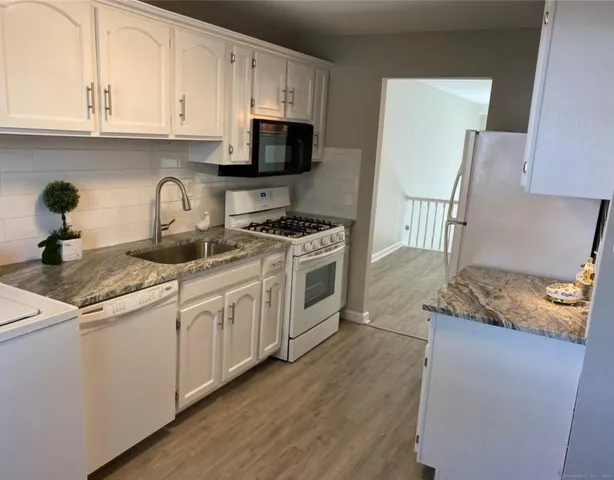 a kitchen with granite countertop a sink a stove and cabinets