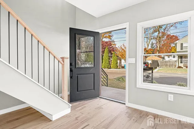 a view of an empty room with wooden floor and stairs