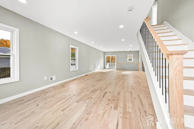 a view of a livingroom with wooden floor and staircase