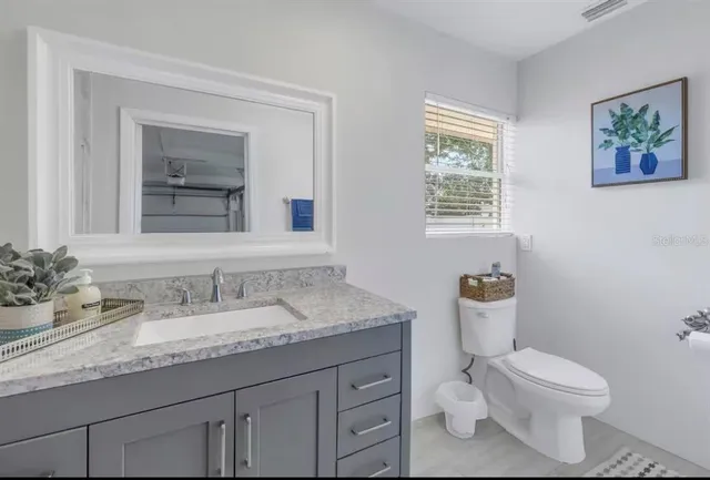 a bathroom with a granite countertop toilet sink and mirror