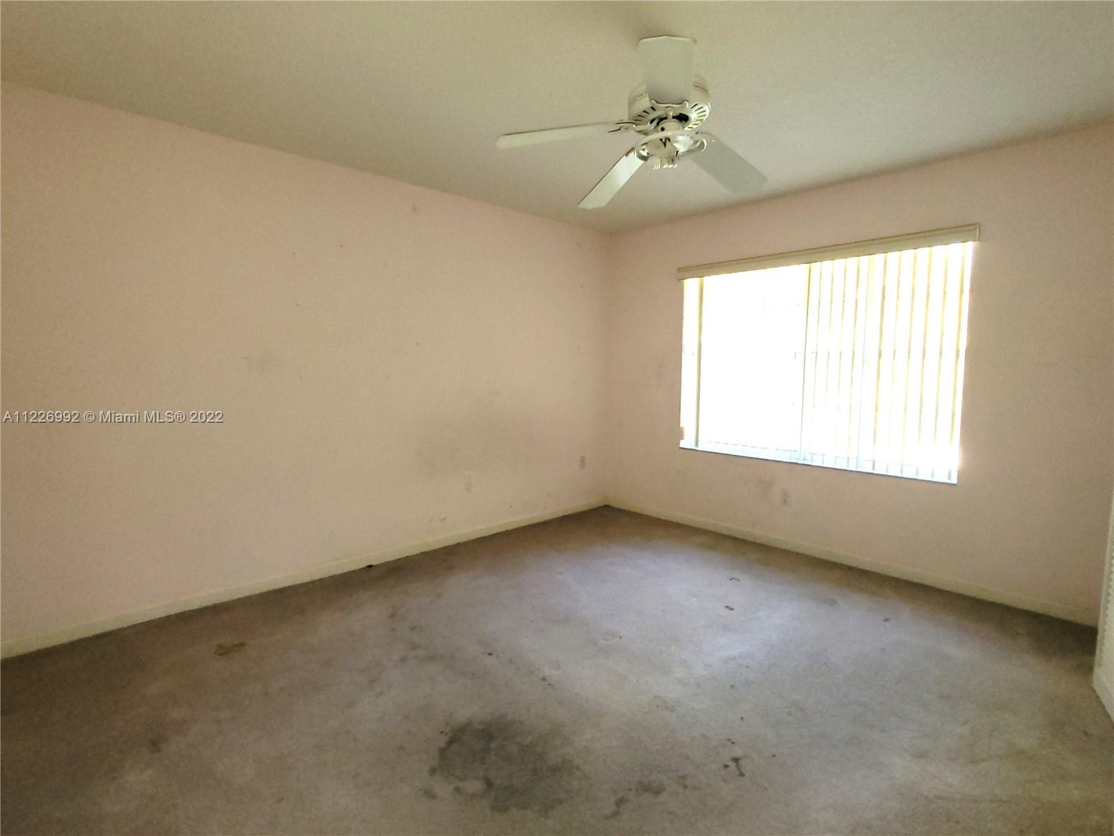 14830 Southwest 149th Street Miami, FL 33196 - Photo 19 of 25 an empty room with a chandelier fan and windows