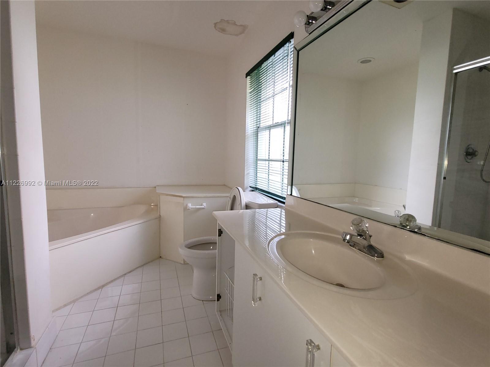 14830 Southwest 149th Street Miami, FL 33196 - Photo 9 of 25 a bathroom with a granite countertop sink a toilet and bathtub