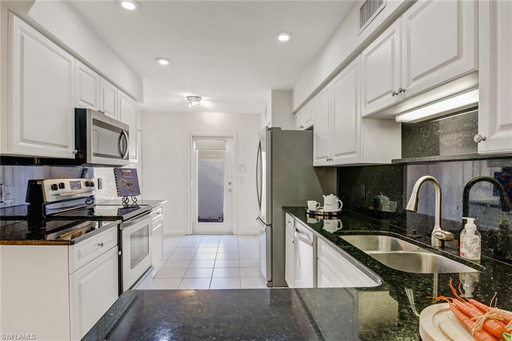 a kitchen with stainless steel appliances granite countertop a refrigerator a sink a stove a microwave and cabinets