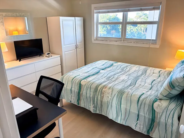 a bedroom with a bed tv and a window