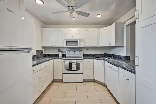 a kitchen with granite countertop white cabinets white stainless steel appliances with a sink and dishwasher