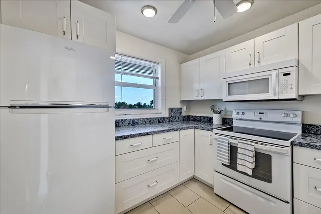 a kitchen with granite countertop white cabinets and white appliances