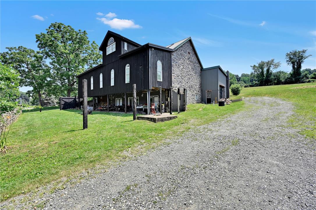 101 Conrad Road Fleetwood, PA 19522 - Photo 41 of 42 An impressive black-sided and stone-clad structure with a sprawling gravel driveway and expansive green lawns.